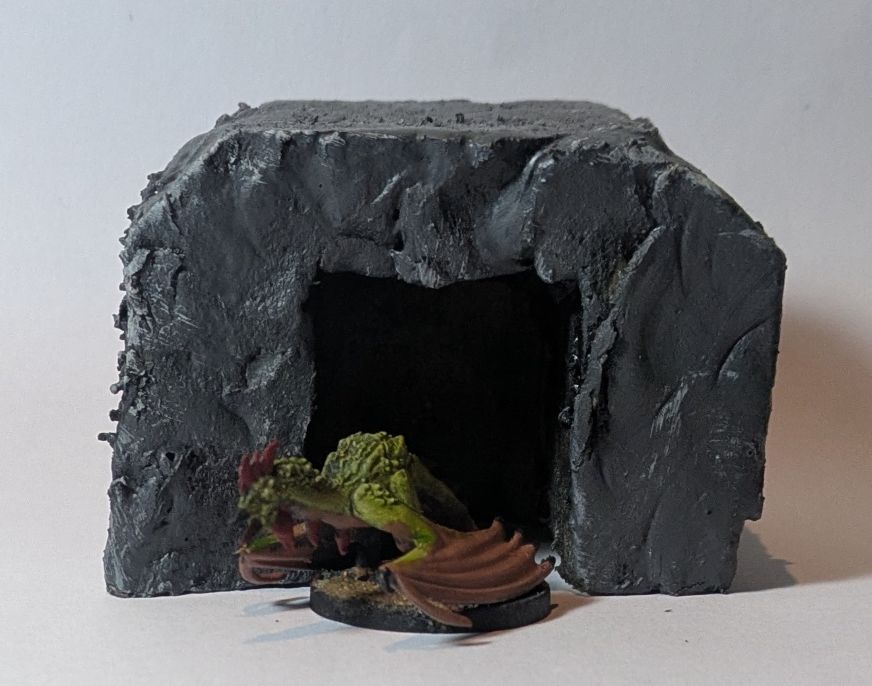 A cocatrix near the entrance of a stone grotto.