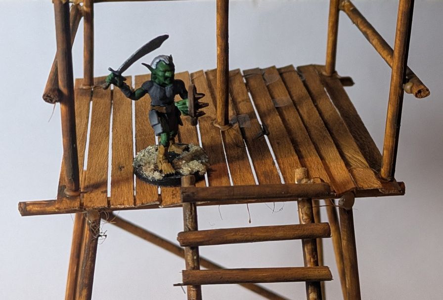 A gobelin with a sword and shield, on the top of a tower.