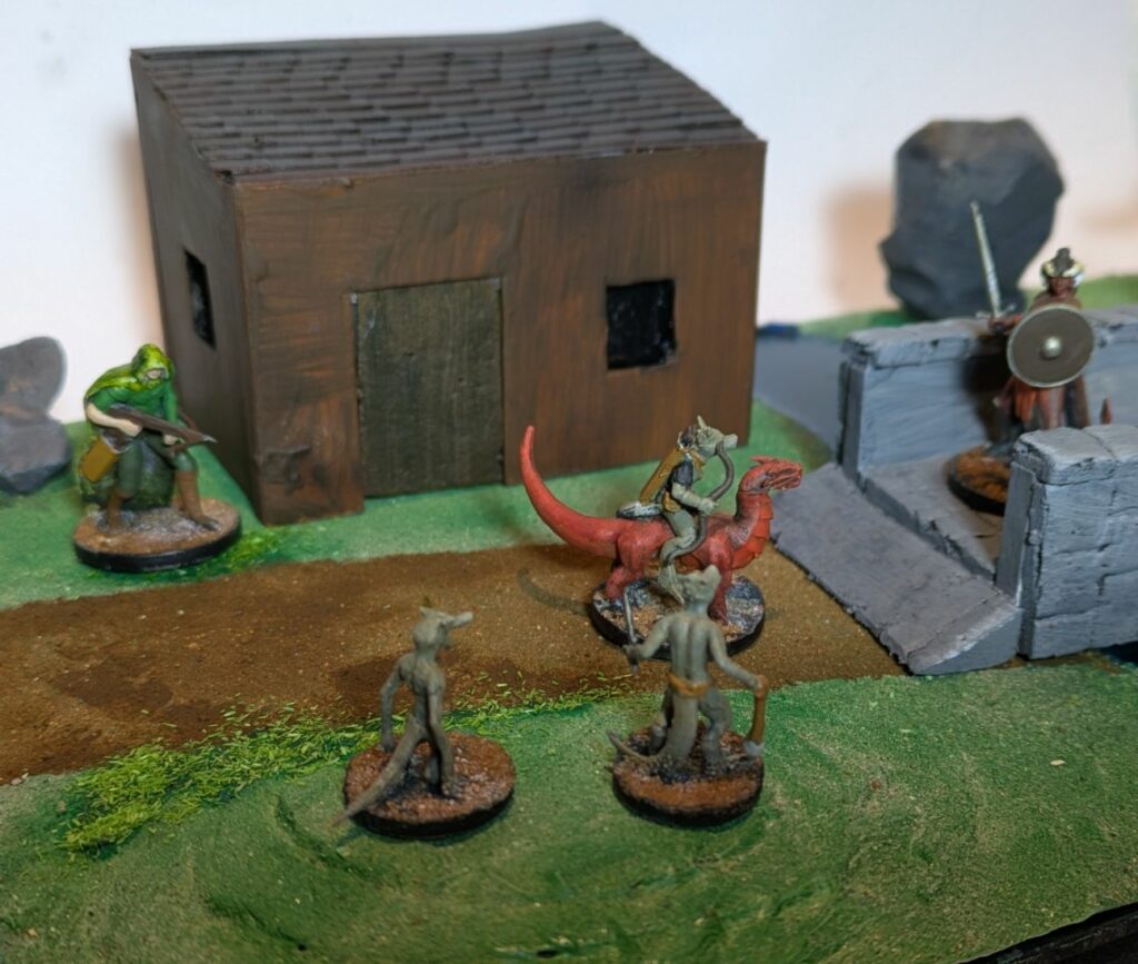 3 small grey monsters are facing a tieffelin warrior. One of the monster is riding a small red dragon. The tiefelin is on a bridge. A man with a crossbow is looking at them from behind.