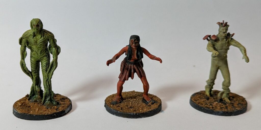 A swamp-thing monster, a grey zombie and a red hag.